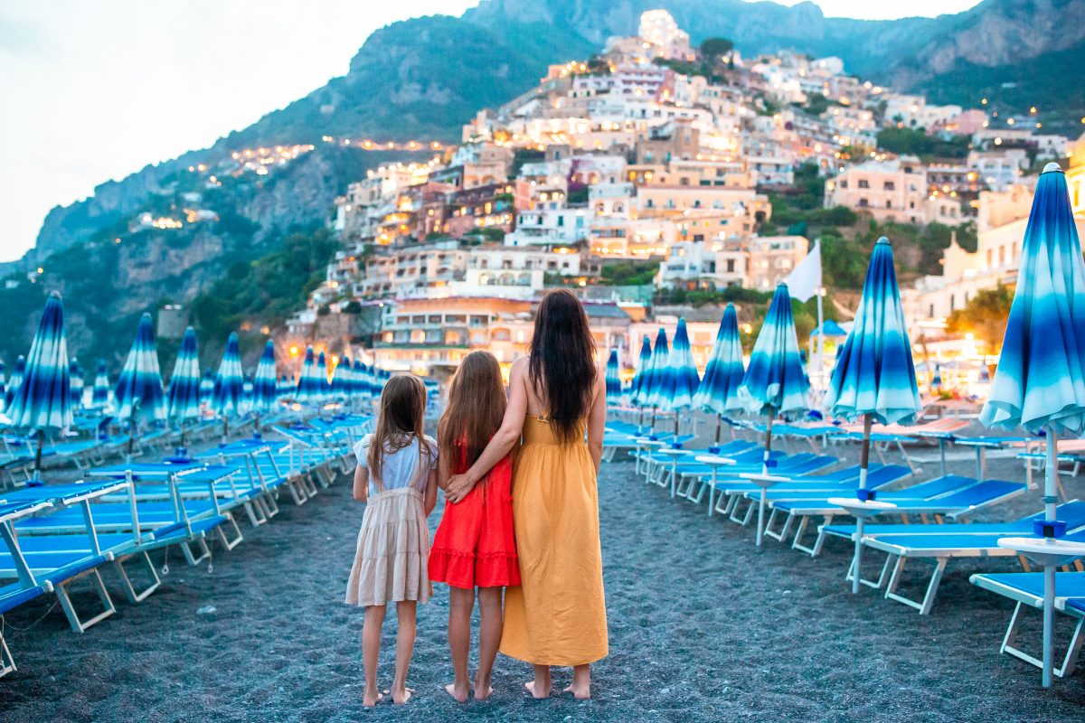 Family embraced on the beach of the Amalfi coast looking towards Positano