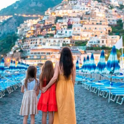 Famiglia abbracciata sulla spiaggia della costiera amalfitana guardando verso positano