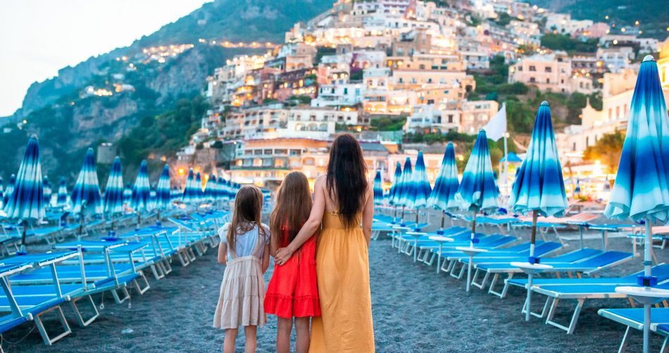 Familia abrazada en la playa de la costa de Amalfi mirando hacia Positano