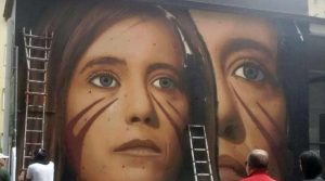 Jorit vervollständigt das Wandgemälde auf Ilaria Cucchi und sein kriegerisches Gesicht erscheint in Neapel