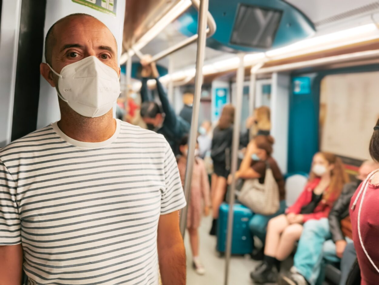 Mann mit ffp2-Gesichtsmaske, der mit U-Bahn, U-Bahn, U-Bahn, öffentlichen Verkehrsmitteln unterwegs ist