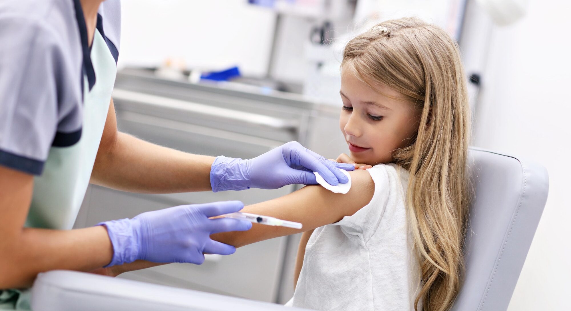 Smiling little girl who is receiving a vaccine