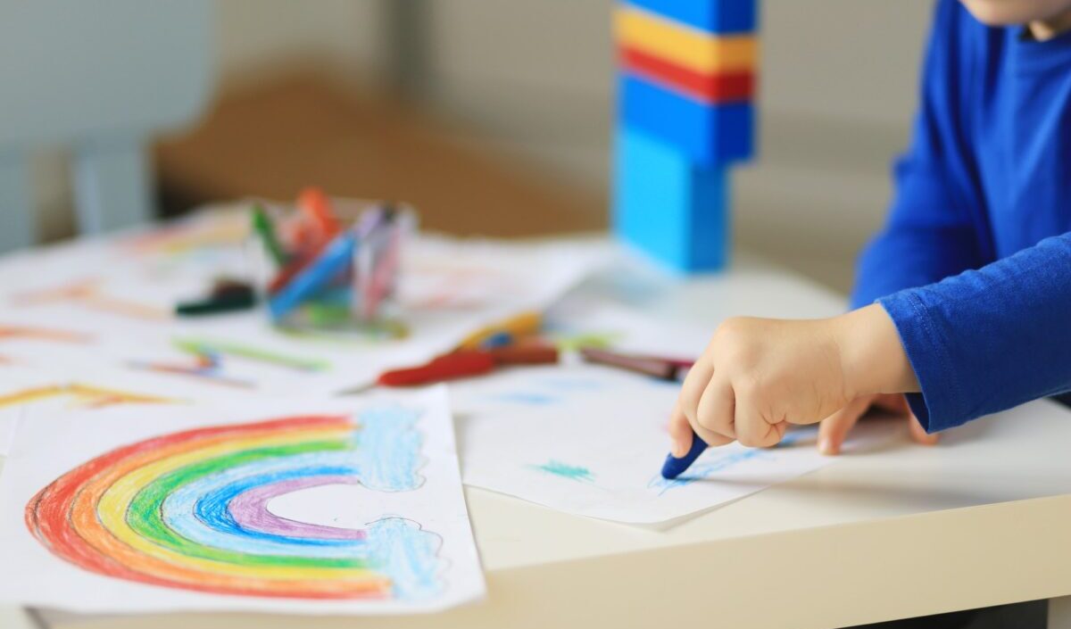 Child hand drawing rainbow