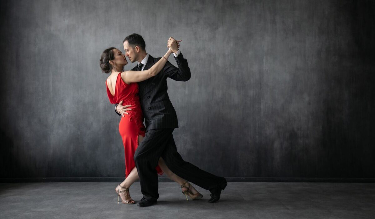 Casal de dançarinos de tango posam em um movimento de dança