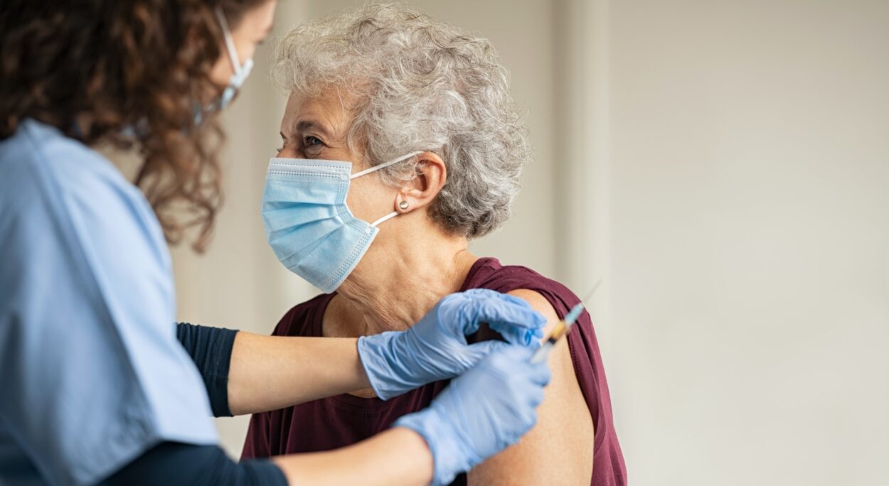 Doctor dando una vacuna a una anciana