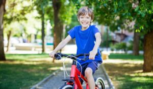 Niño feliz montando una bicicleta en el parque