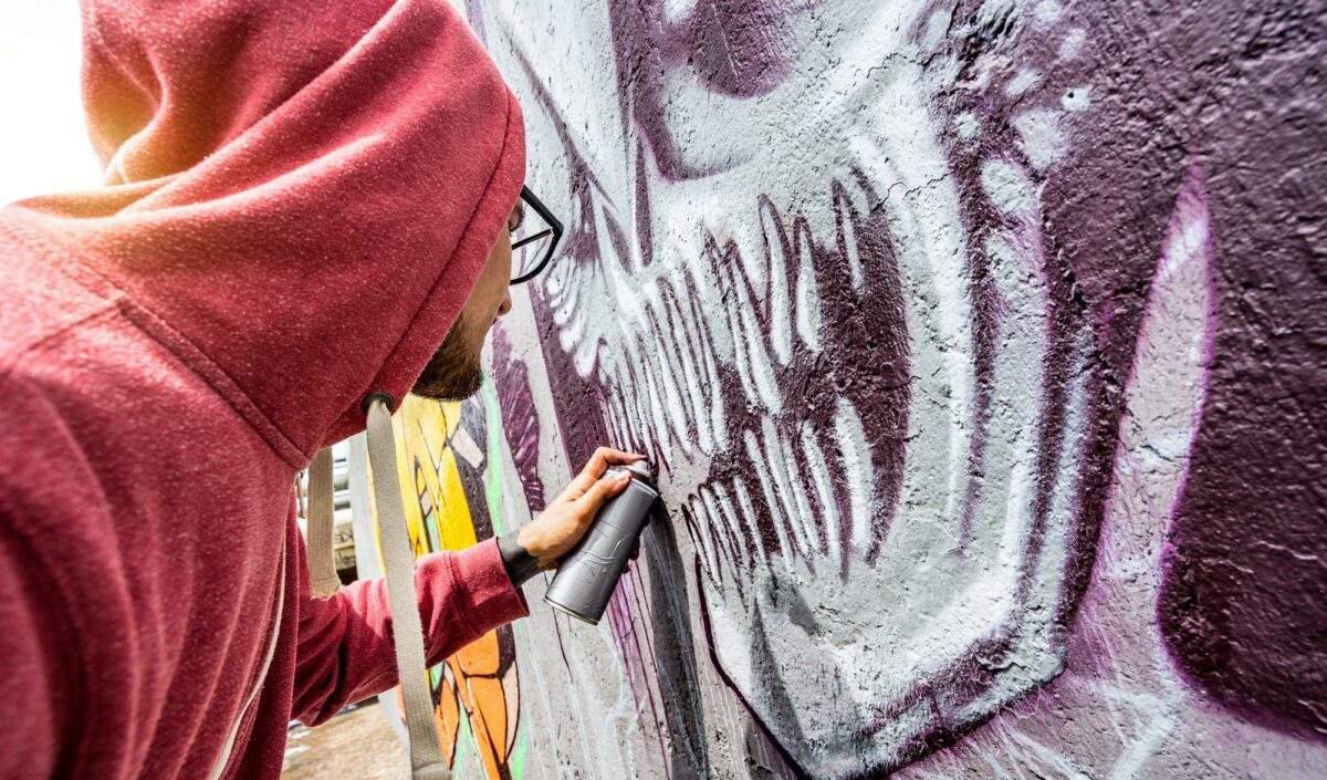 Street artist painting colorful graffiti on public wall