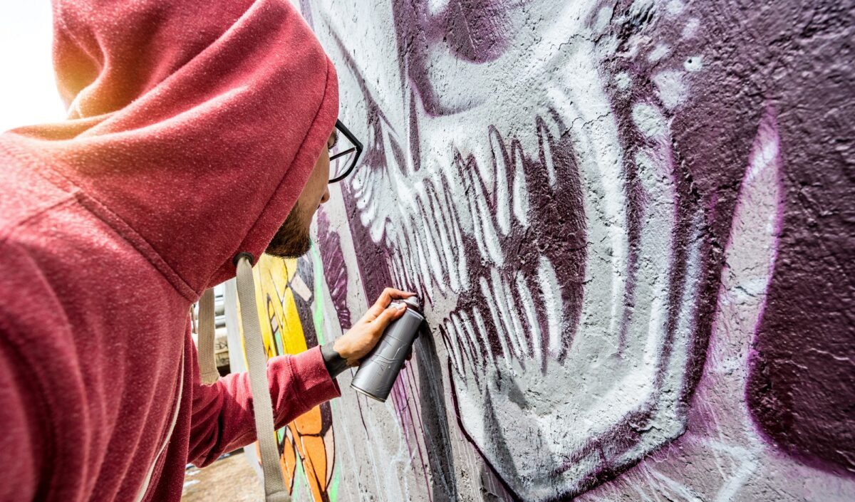 Artiste de rue peignant des graffitis colorés sur un mur public