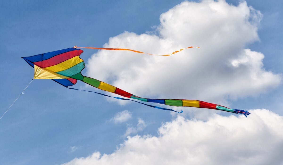 Buntes Drachenfliegen am bewölkten Himmel. Sommerferienkonzept. Farben im Retro-Stil