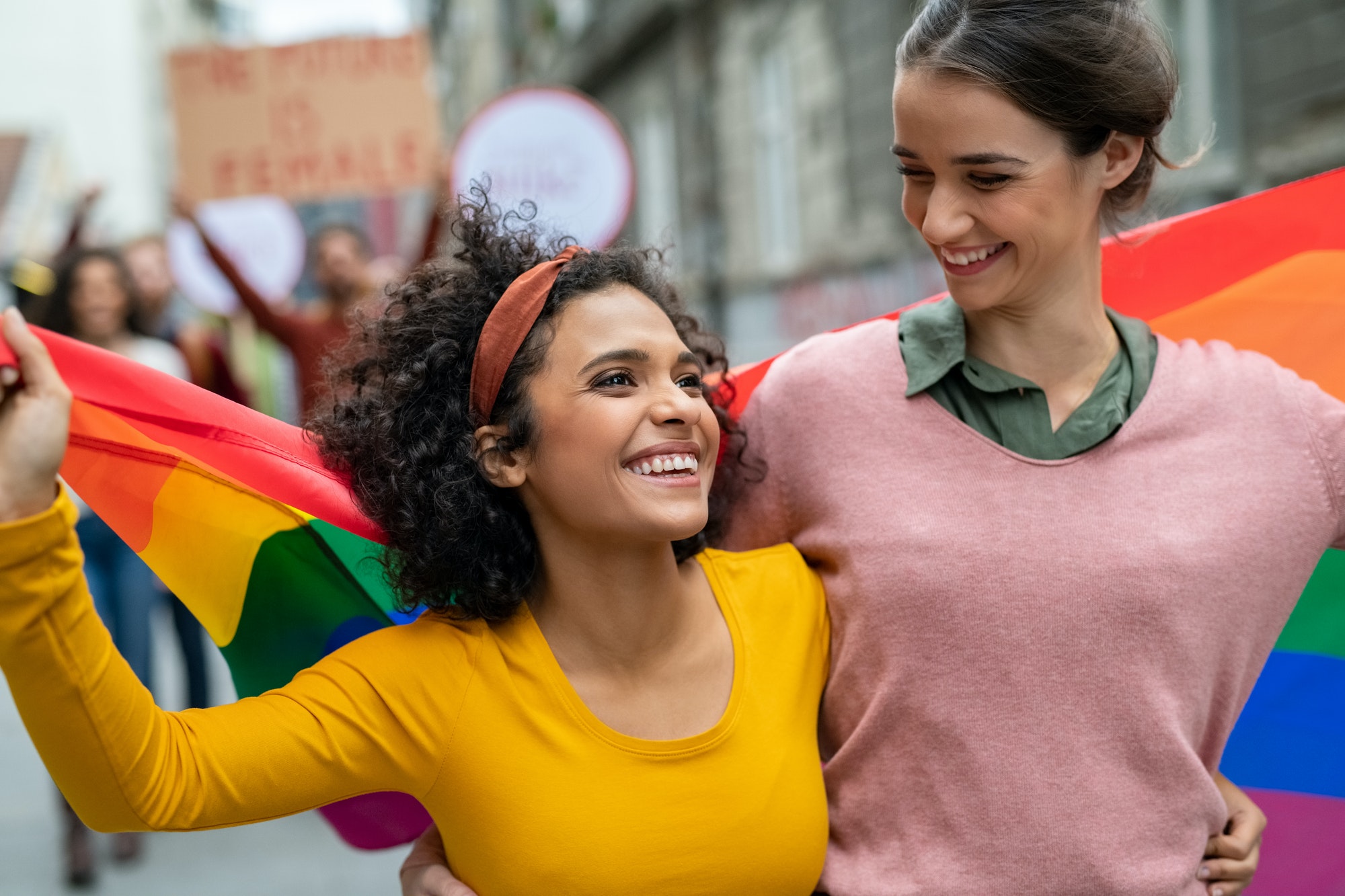 Couple de lesbiennes à la gay pride avec drapeau arc-en-ciel