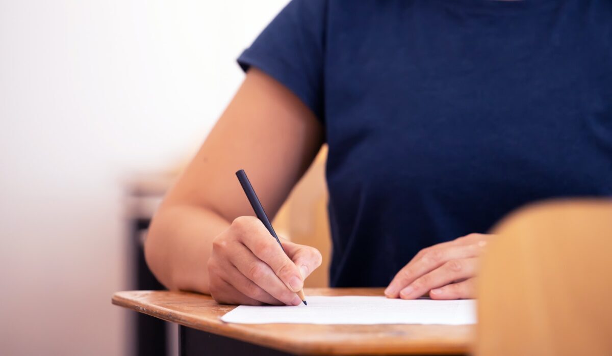 Student writing final exam in classroom.