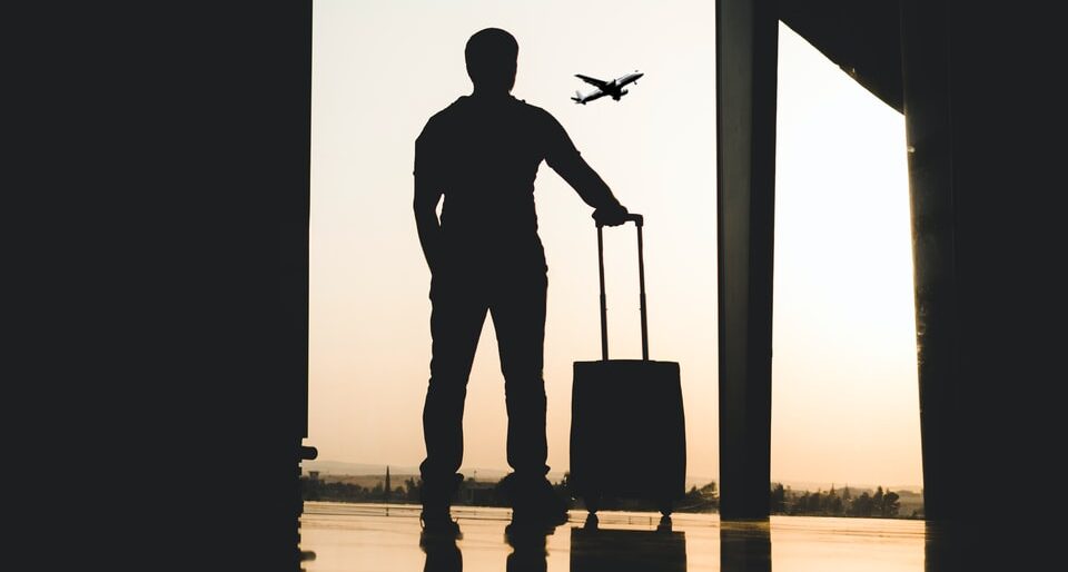 Silhouette eines Mannes, der Gepäck im Flughafen hält