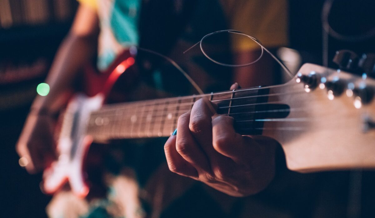 Feche o músico jovem tocando guitarra elétrica