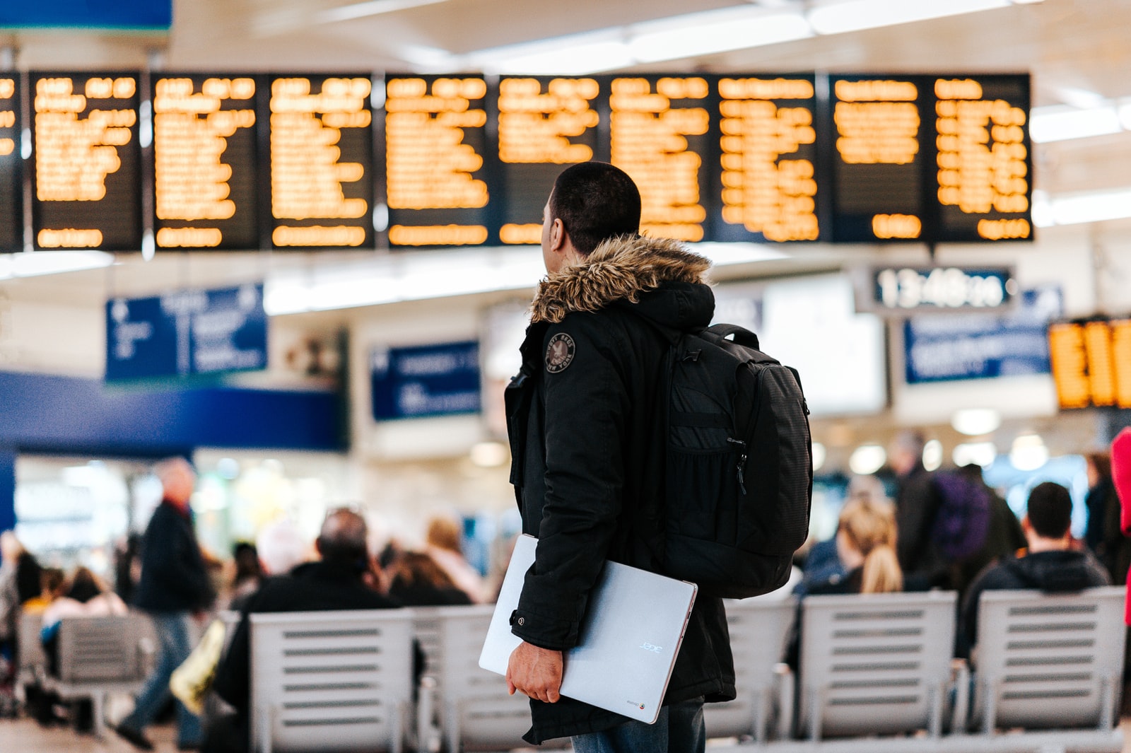 hombre de pie dentro del aeropuerto mirando el tablón de anuncios de horarios de vuelos LED