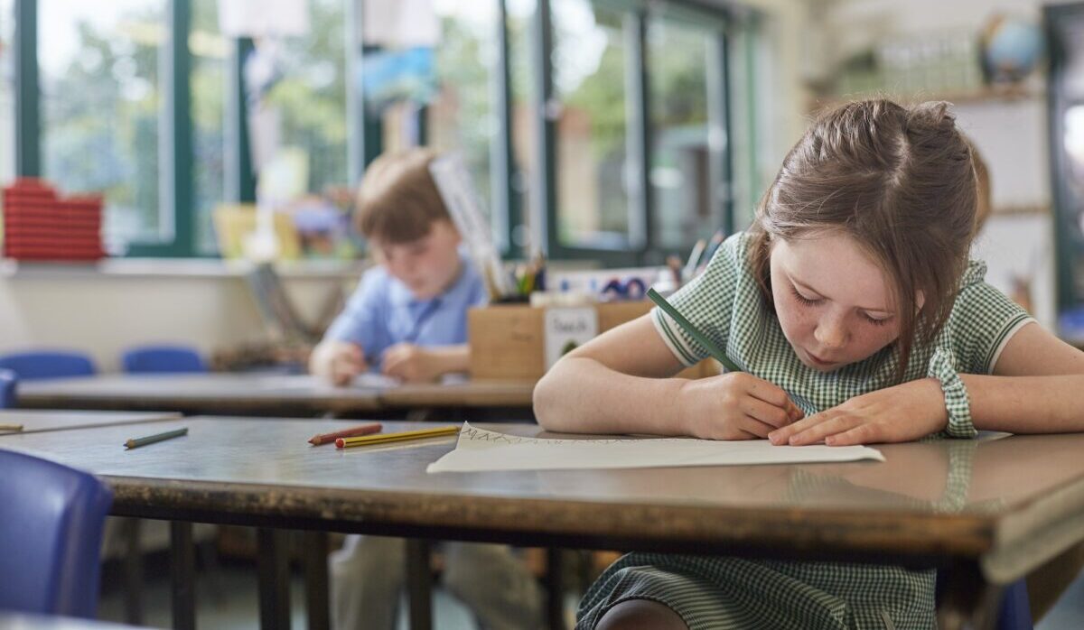 Schoolgirl writing in classroom lesson in primary school