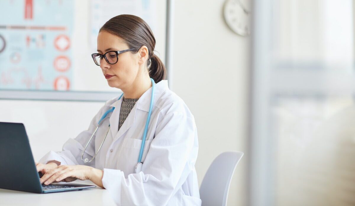 Médico trabalhando com laptop no escritório