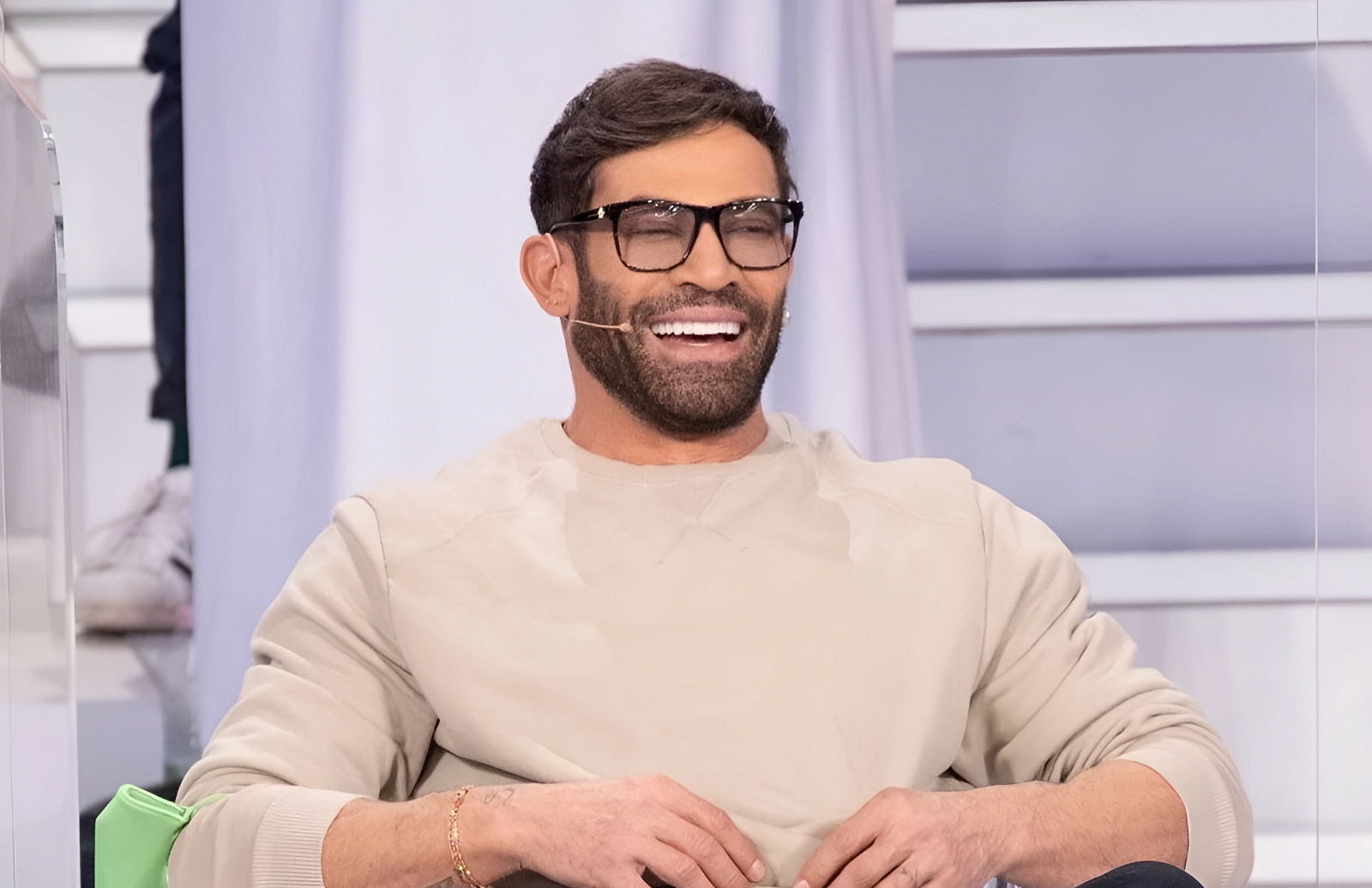 Half-length photo of Gianni Sperti seated during an episode of Men and Women