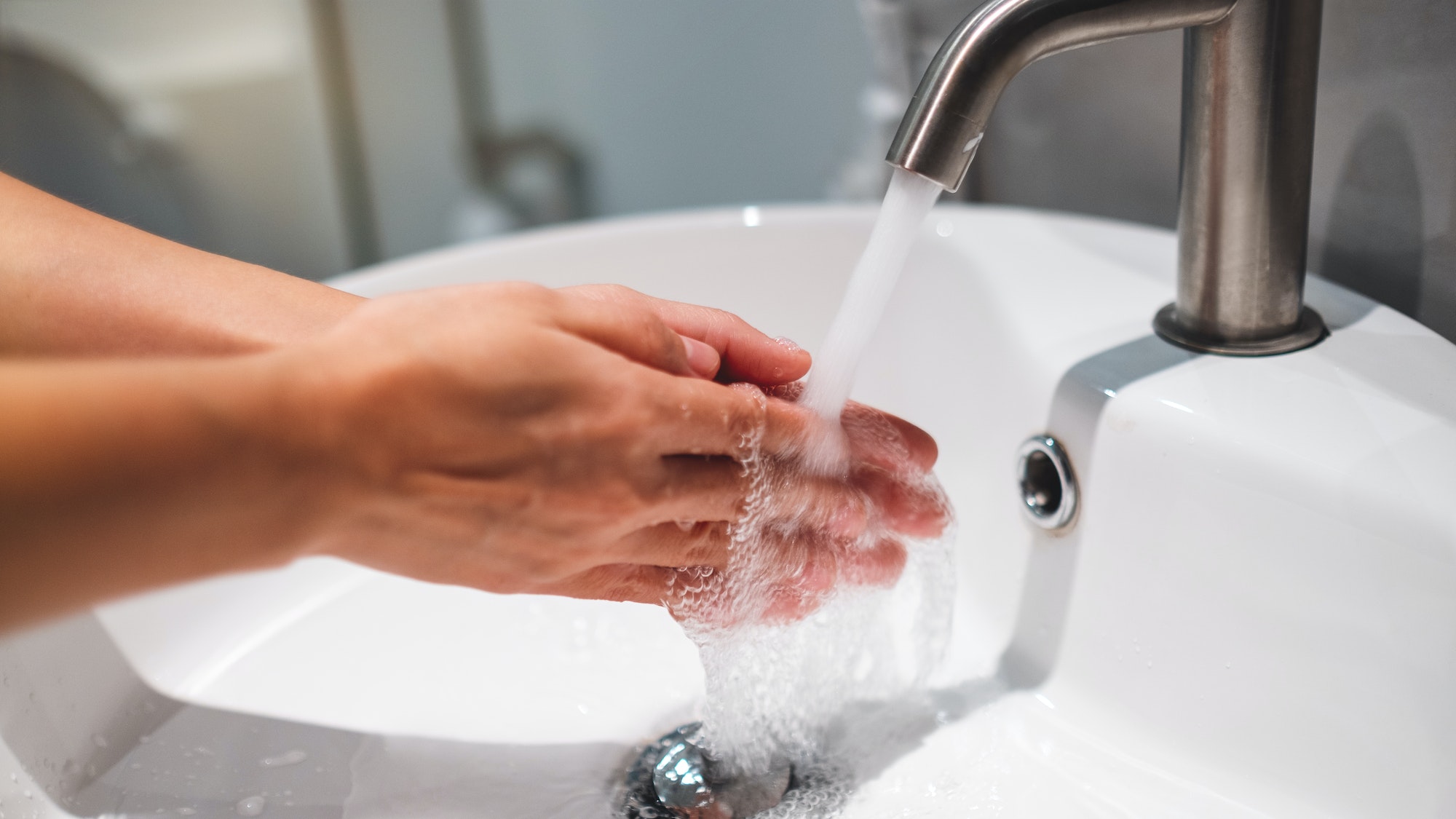 mujer, limpieza, y, lavado, manos, debajo, el, grifo, en, cuarto de baño