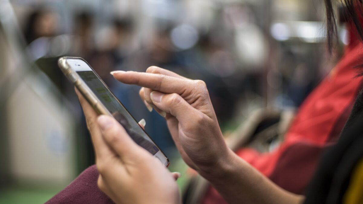 A mulher asiática senta-se no metrô e segura o smartphone. Passageiro usando telefone