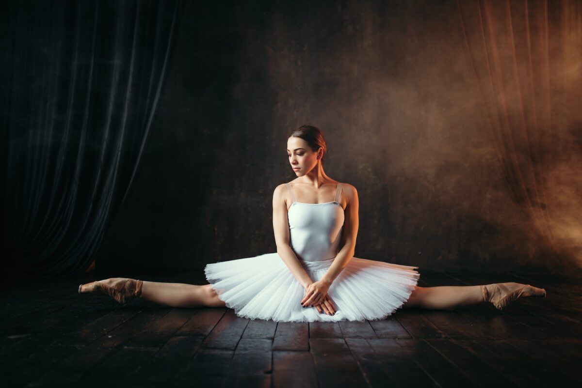 Ballerina in white dress sits on a twine