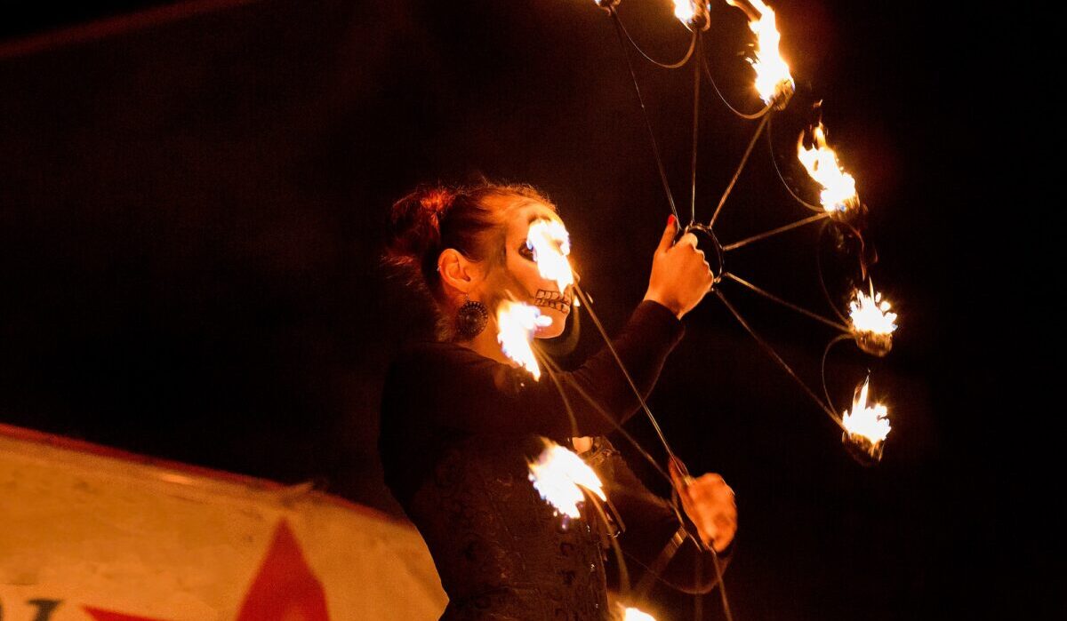 ↟ Feuershow. Feuertänzerin tanzt. Nachtvorstellung. Dramatisches Porträt. Feuer und Rauch