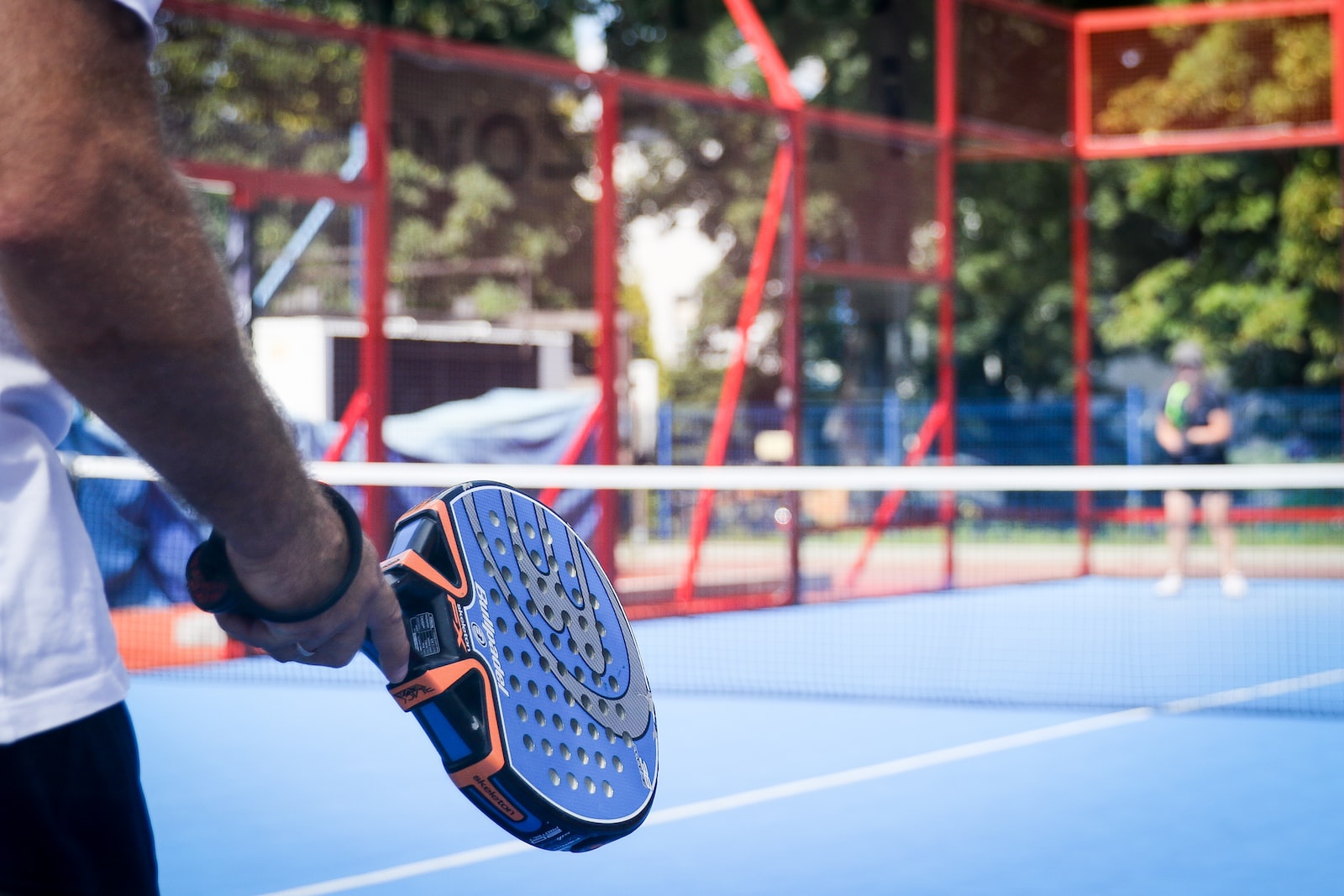 Person, die Padel auf einem Außenplatz spielt