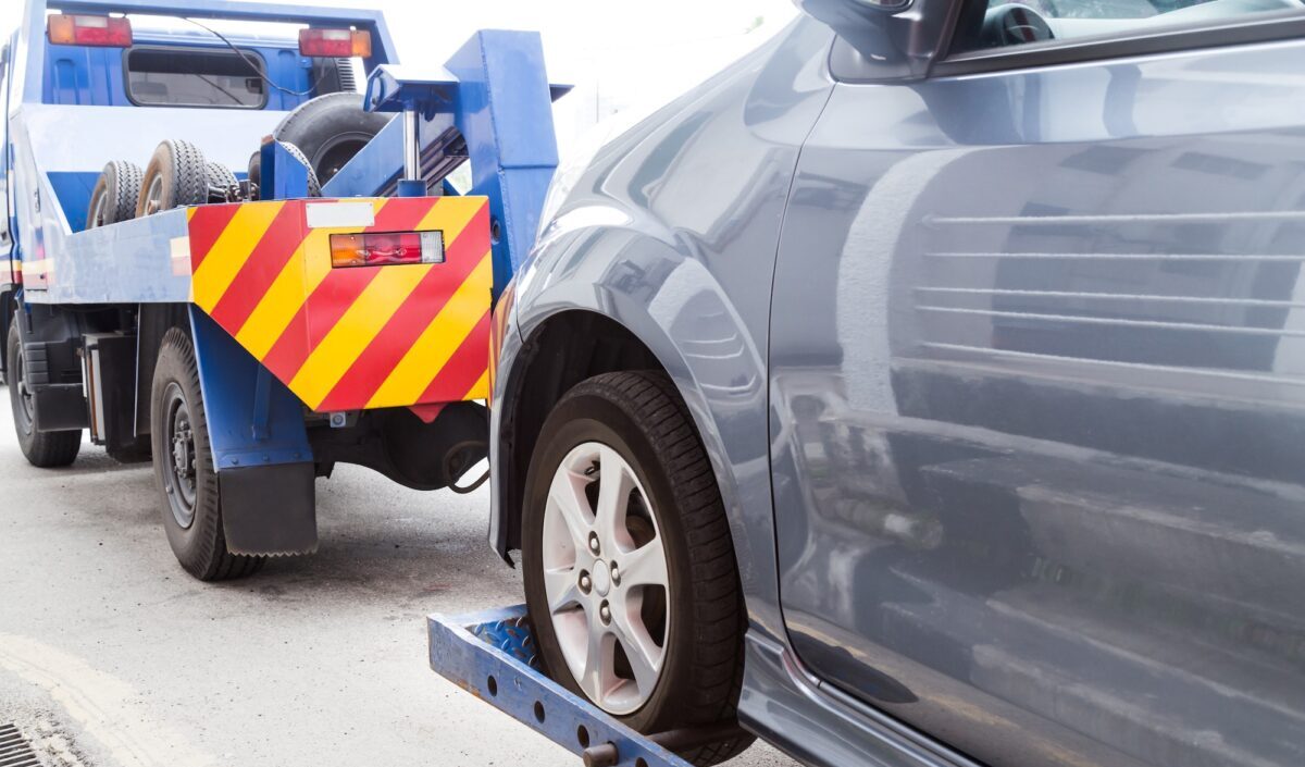 Tow truck towing a broken down car on the street