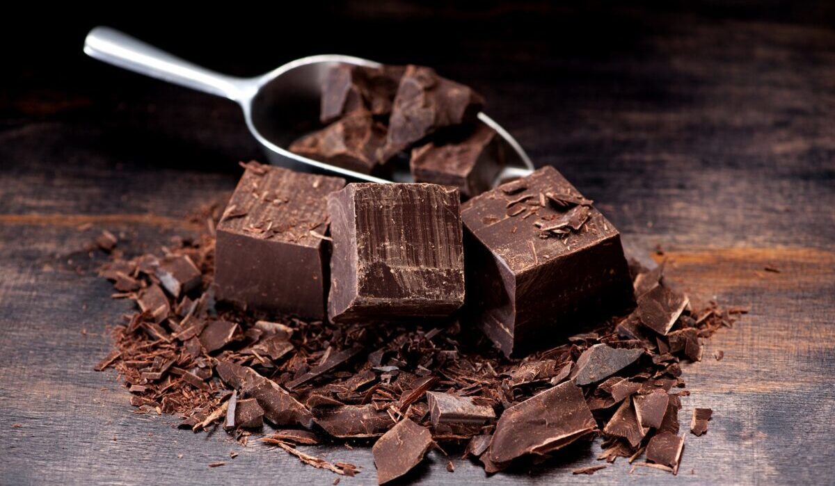 Dark chocolate in a metal scoop and on a table