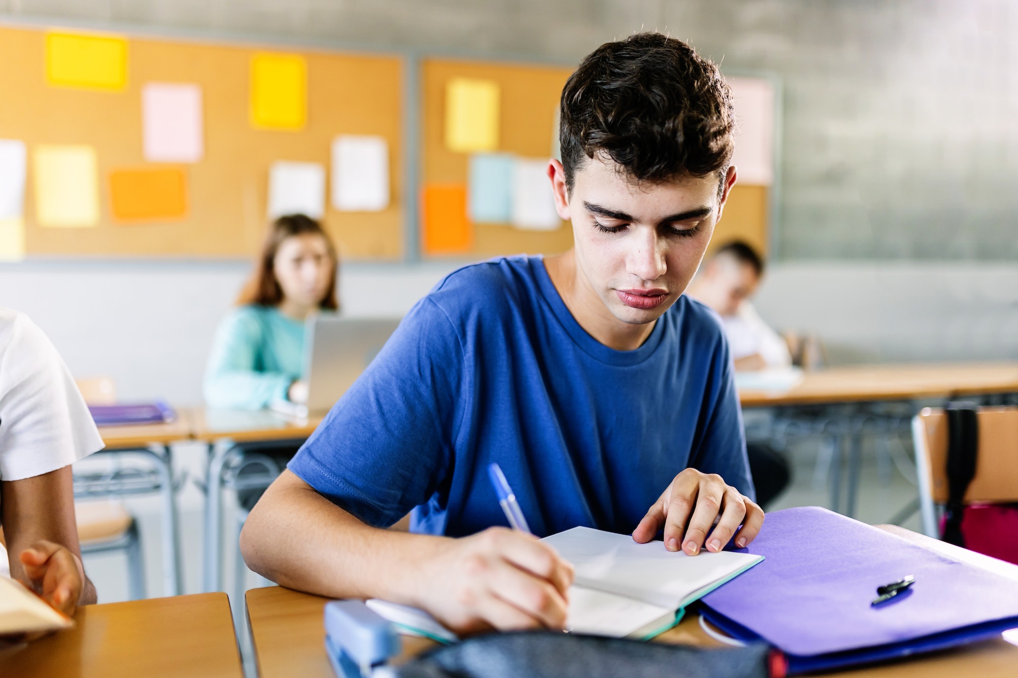 Highschool-Schüler, der in der Klassenvorlesung in ein Notizbuch schreibt