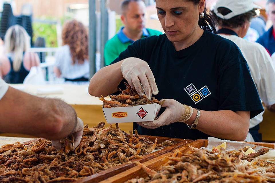 Cuoca che prepara porzioni di pescato di Paranza