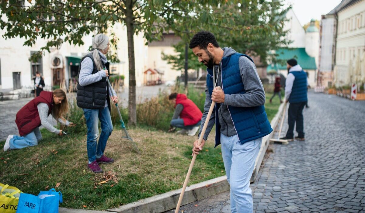 Joven voluntario con equipo limpiando calles, concepto de servicio comunitario