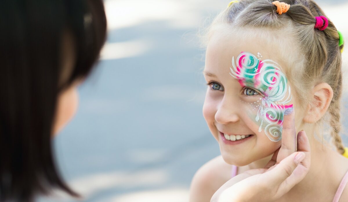 Petite fille se faisant peindre le visage par un artiste de maquillage.