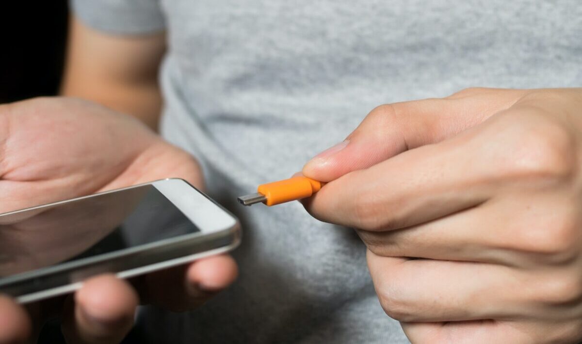 Homem carregando seu celular com porta de energia