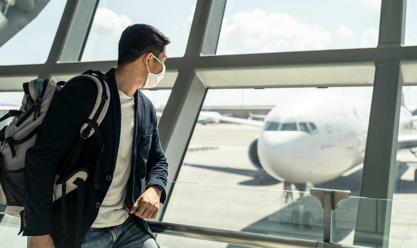 Ein asiatischer Geschäftsreisender wartet im Abflugterminal des Flughafens darauf, ins Flugzeug einzusteigen