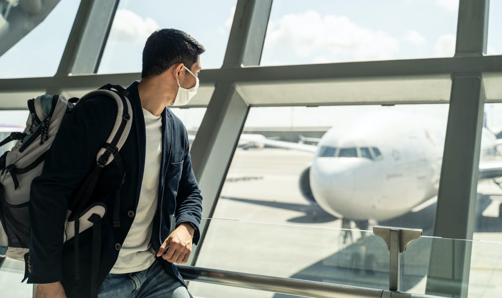 Homem de negócios viajante asiático espera para embarcar no avião, parado no terminal de embarque no aeroporto