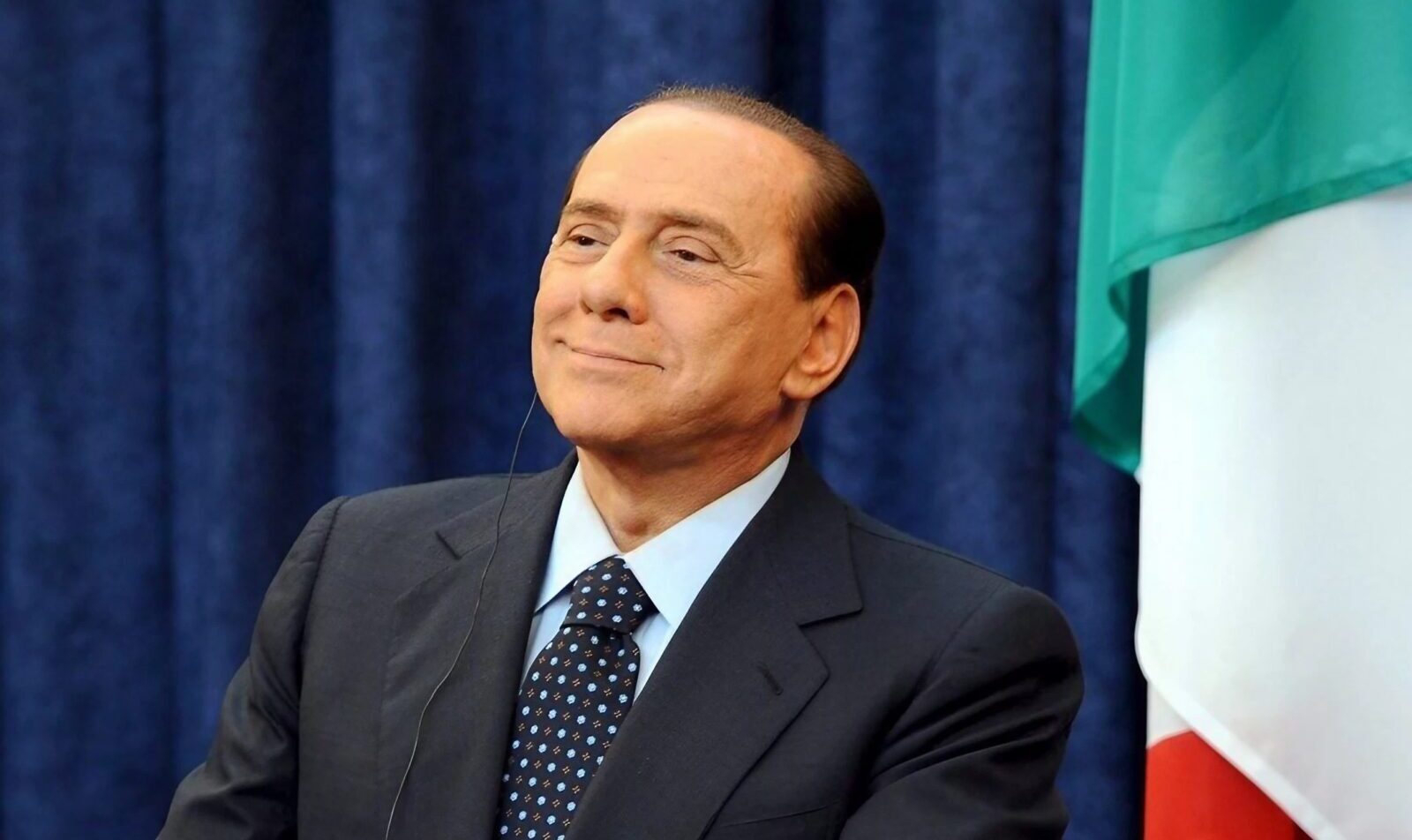 Silvio Berlusconi a mezzobusto con la bandiera italiana