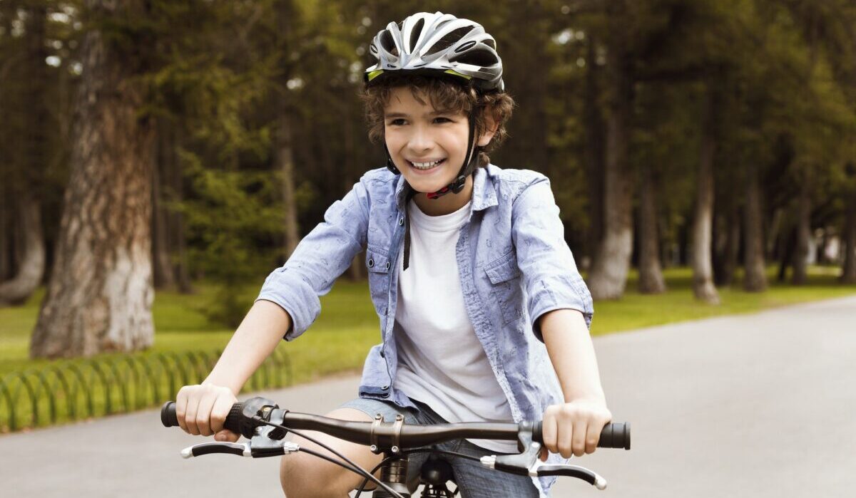 Menino aprendendo a andar de bicicleta no parque