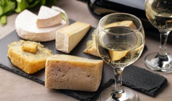 Different types of cheese and wine on gray table