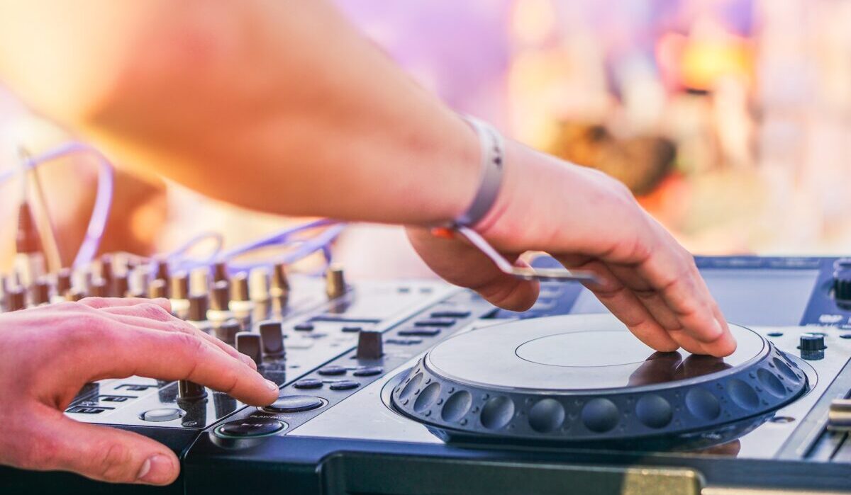 Dj mixando no festival de festa na praia com pessoas dançando ao fundo