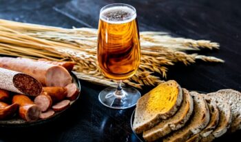 glass of beer, sausages and bread on the table