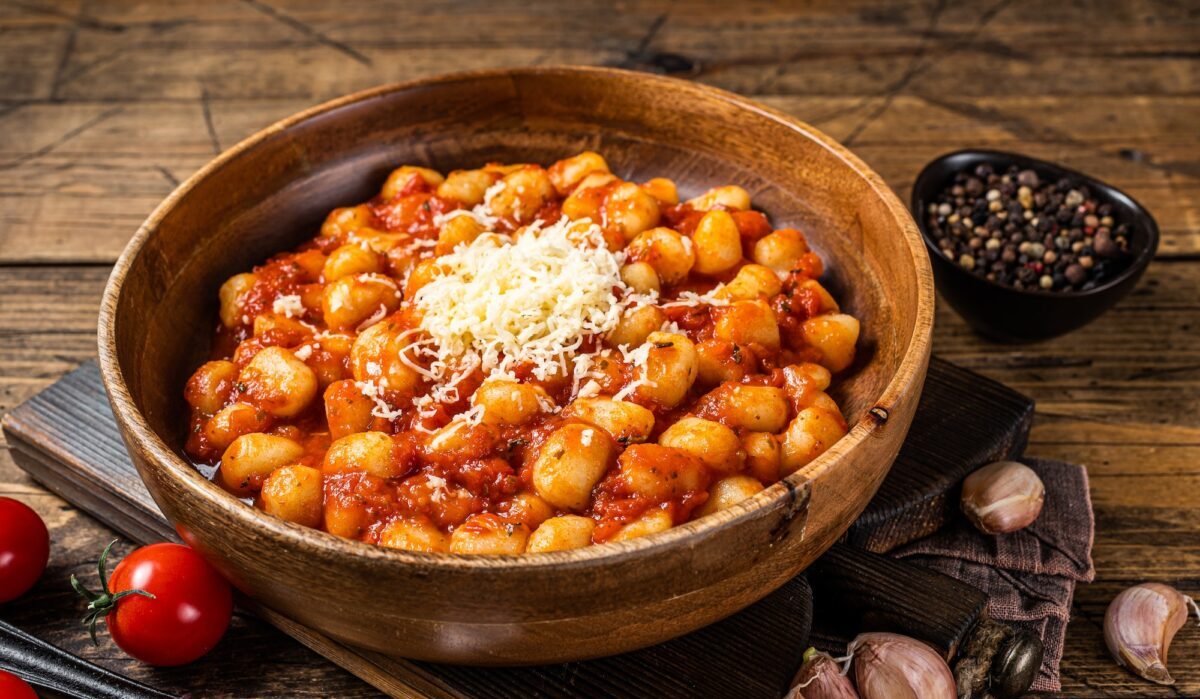 Pasta de patata ñoquis italianos en salsa de tomate. Fondo de madera. Vista superior