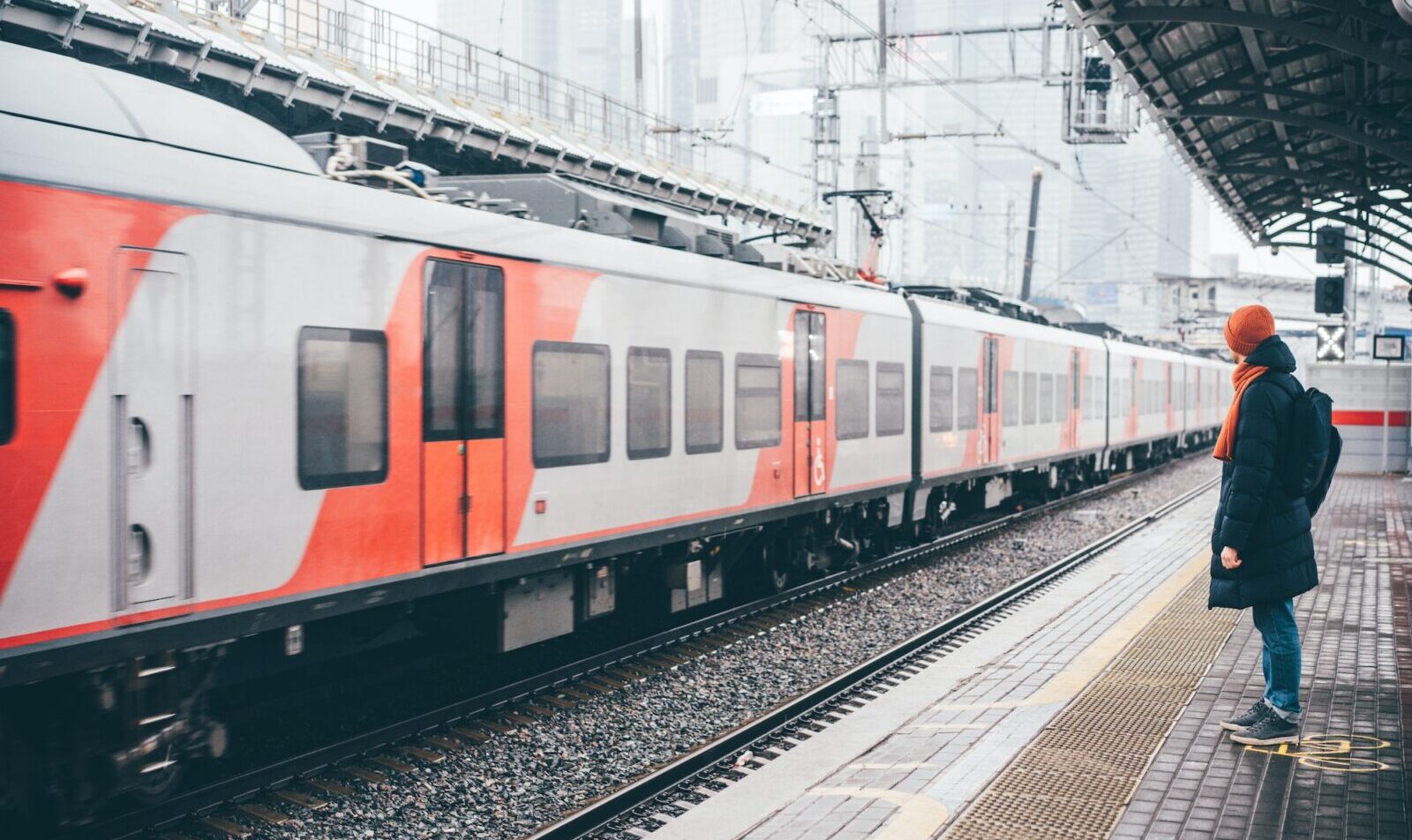 ヨーロッパの駅で電車のプラットホームに立って電車を待っている男性。