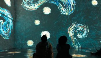 Pessoas sentadas em círculos de distanciamento físico na Exposição Imersiva de Van Gogh em Toronto, Canadá