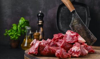 Chopping fresh beef meat on wooden chopping stump