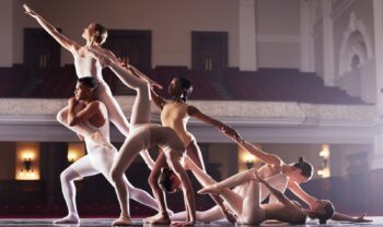 Снимок группы из нескольких артистов балета, выступающих в театре.