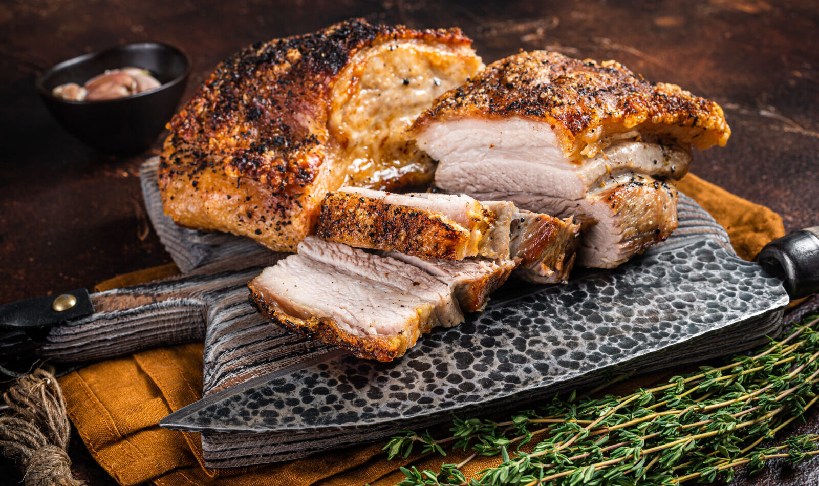 Gebratener Schweinebauchspeck mit Kruste auf einem Holzbrett. Dunkler Hintergrund. Top-Ansichten