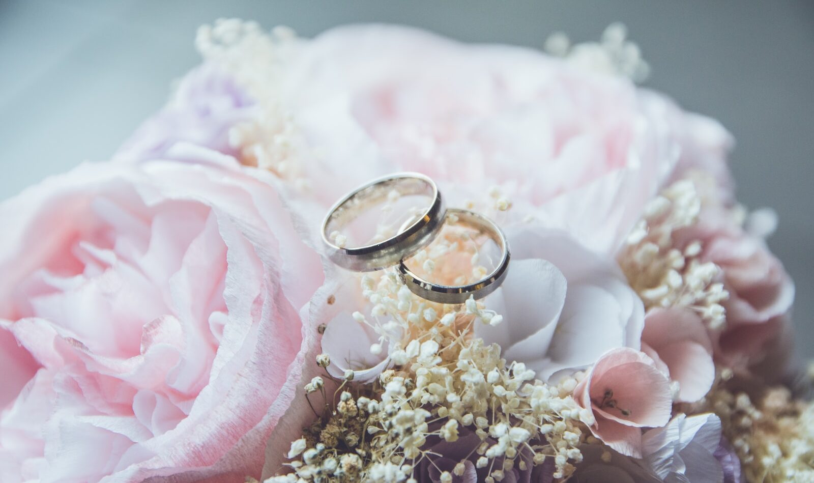 gold-colored bridal ring set on pink rose flower bouquet