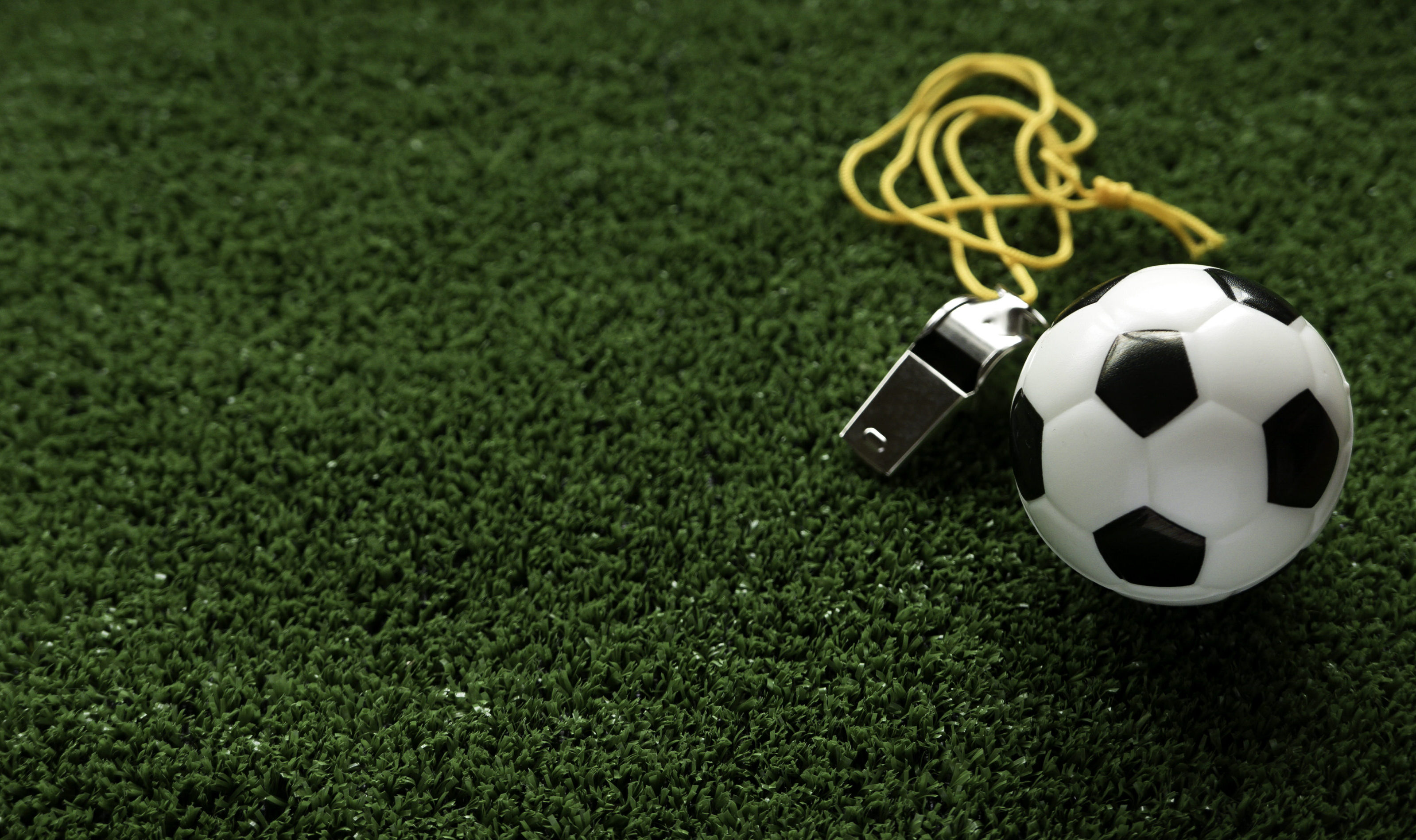 Soccer ball and a whistle on a football field.