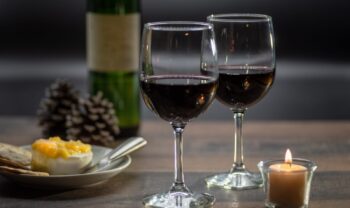 Two glasses of Wine and cheese Brie and crackers on rustic wood table