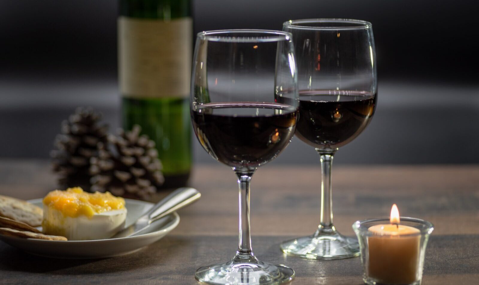 Dois copos de vinho e queijo Brie e biscoitos na mesa de madeira rústica